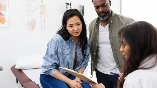 asian and black couple speaking with medical doctor in exam room