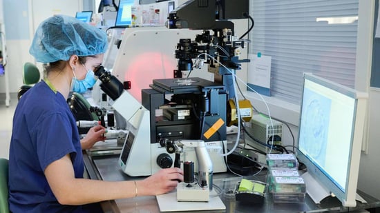 IVF embryologist grading embryos under microscope in fertility clinic laboratory