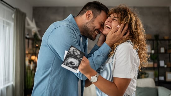 a happy couple celebrates pregnancy news holding ultrasound images