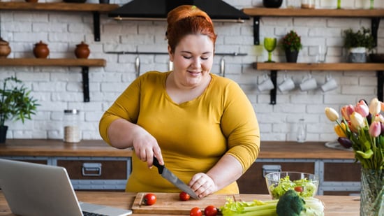 plus size woman chopping vegetables making a salad in kitchen
