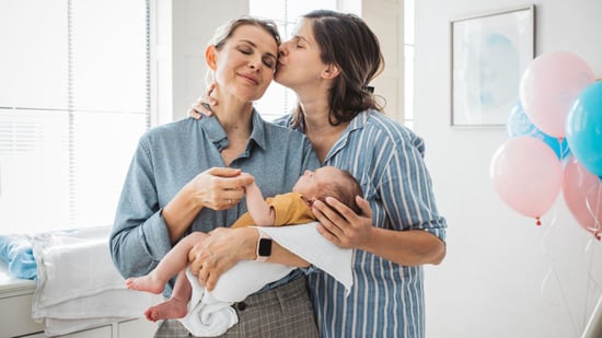 LGBTQ two mom couple holding newborn baby