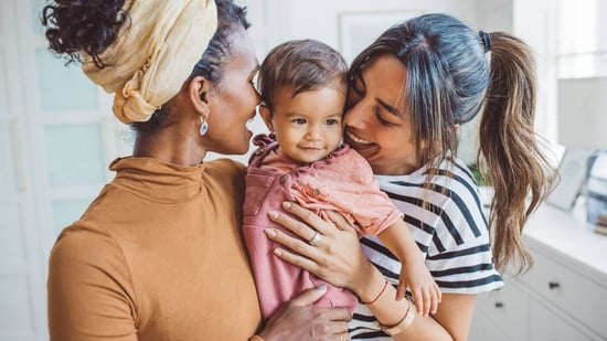 lesbian couple holding their baby and smiling