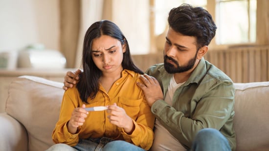 indian woman and man looking at negative pregnancy test