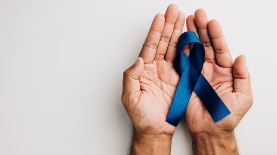 male hands open holding a blue awareness ribbon for men's health