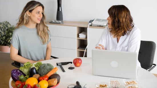 female patient consulting with nutritionist sitting at table with fruits and vegetables