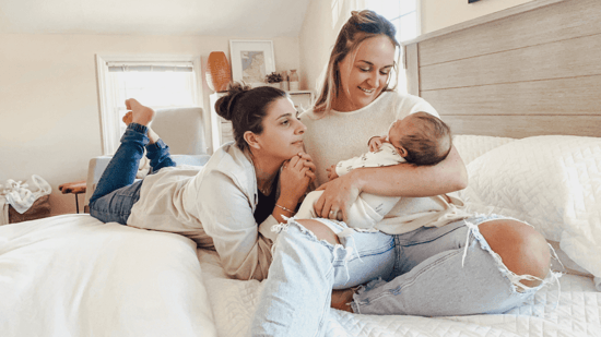 lesbian queer mothers holding newborn baby