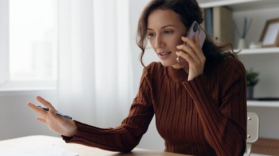 woman holds mobile phone up to ear speaking to insurance representative